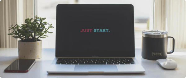 A laptop with a message designed to inspire that reads, JUST START.