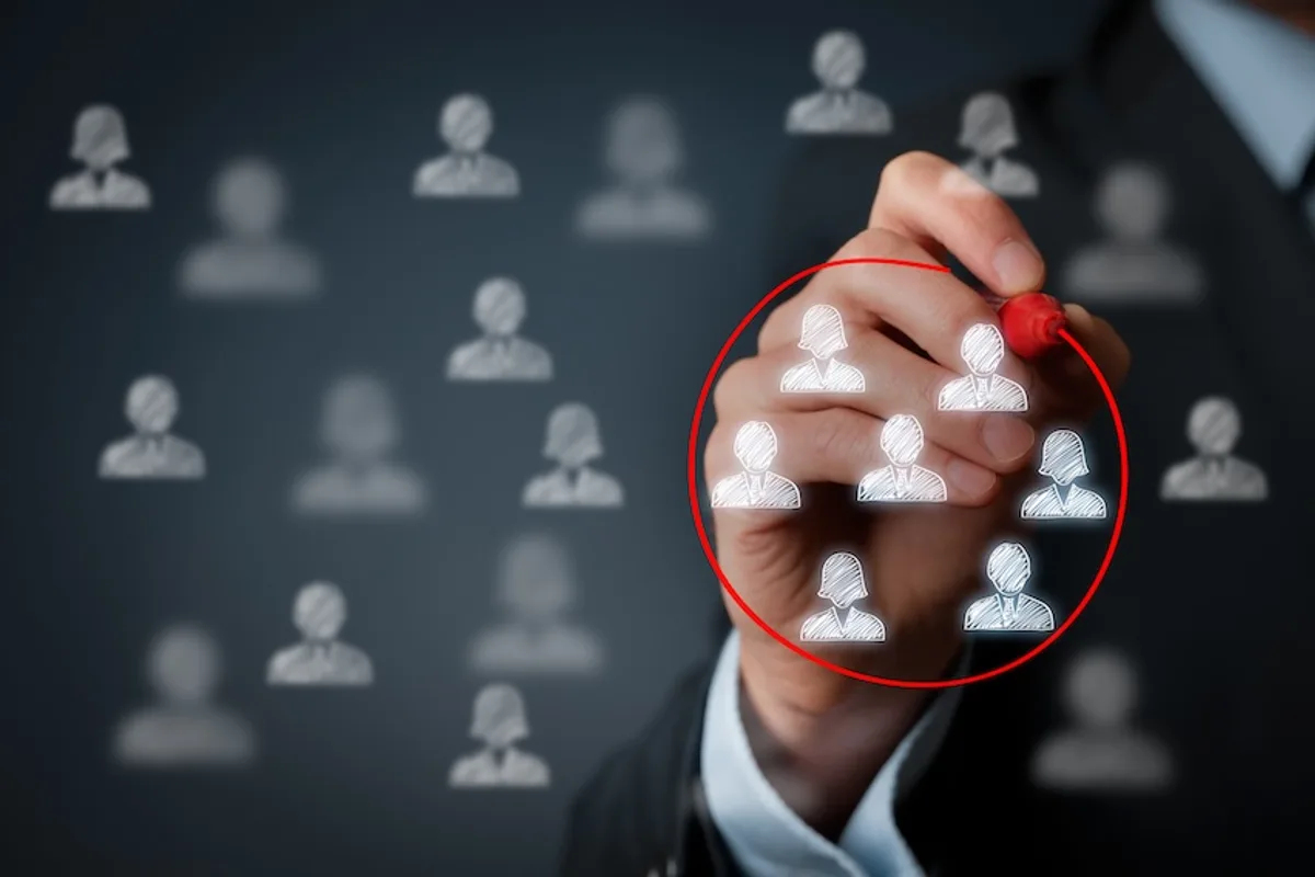 Business hand drawing a circle around customer icons on an invisible board, symbolizing targeted email list segmentation for bulk email campaigns.