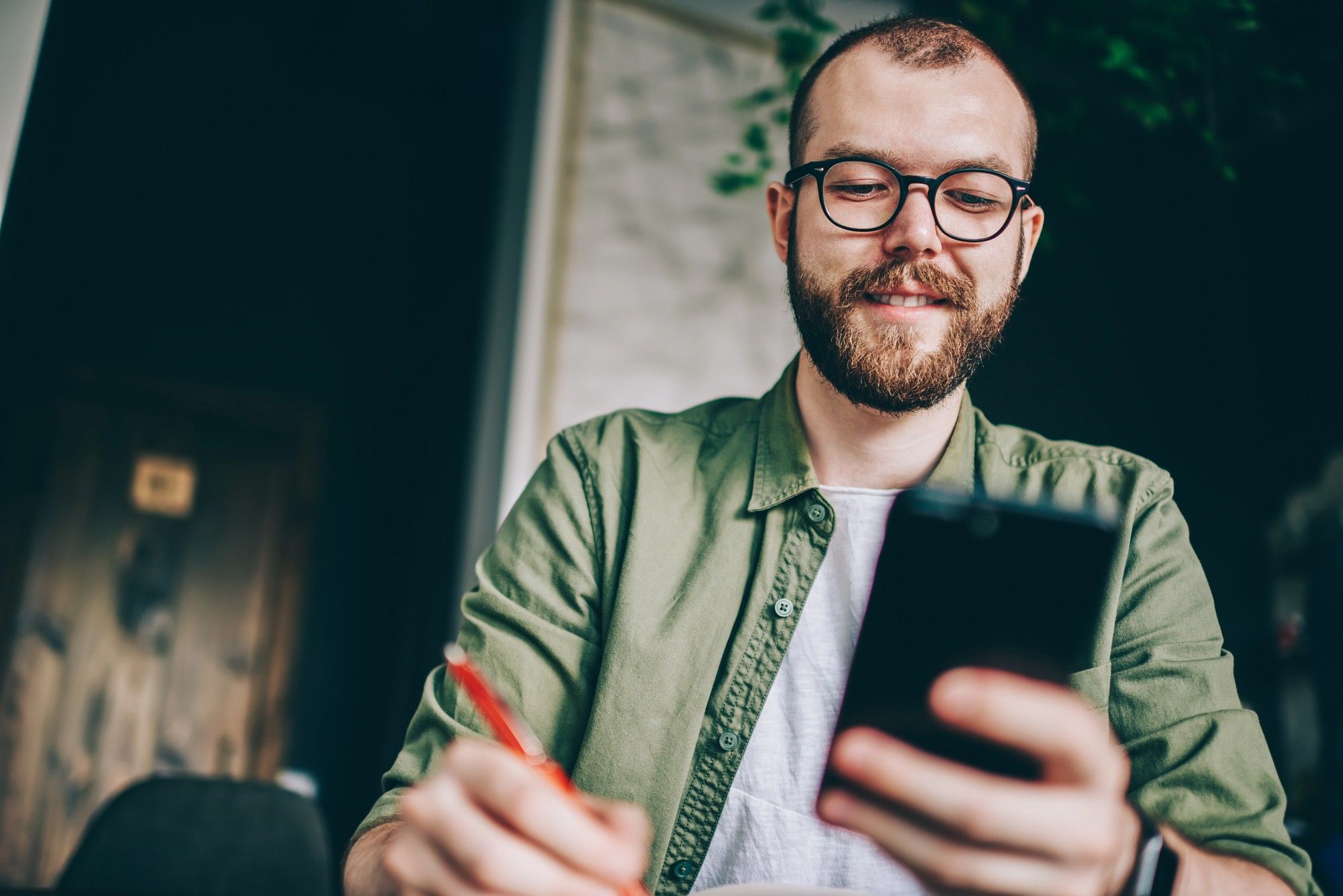 Man smiling while reading personalized email on smartphone, illustrating increased engagement from targeted email marketing.