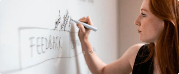 A woman writing on a whiteboard about feedback and email marketing strategies.
