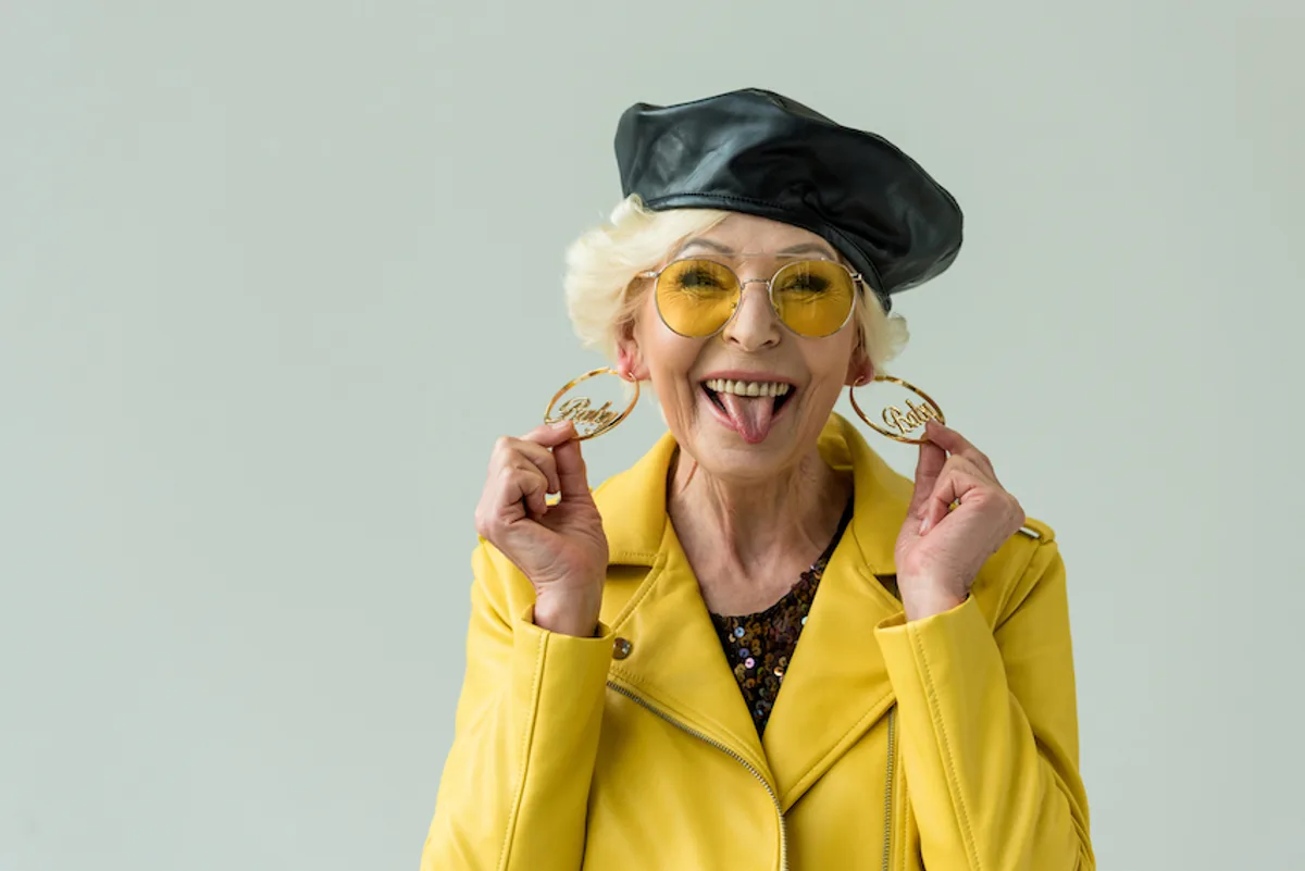 Eccentric lady in lemon yellow jacket, 'Baby' earrings, tongue out, embodies the fun of 'Keep on truckin'' email sign offs.