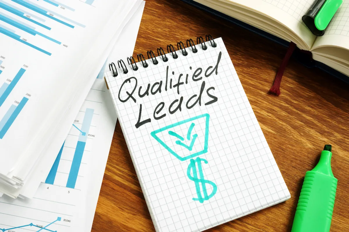 Notebook on desk with 'Qualified Leads', funnel, and dollar sign, symbolizing lead qualification and revenue growth.