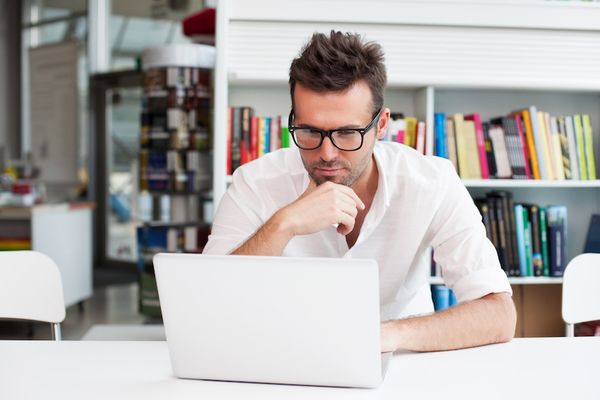 A man looking at bulk email marketing software on his laptop.