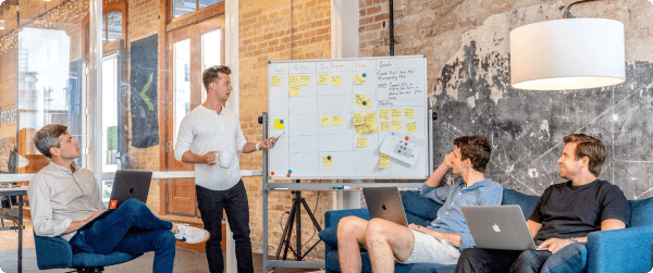 A startup team with one member presenting SEO strategies on a whiteboard.
