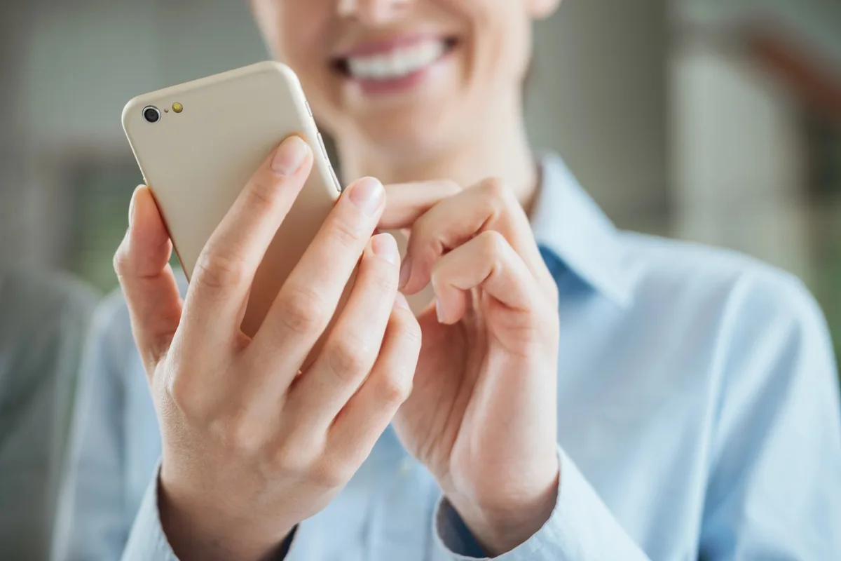 Woman reading a clear, mobile-friendly newsletter on her smartphone, illustrating the importance of responsive newsletter design.