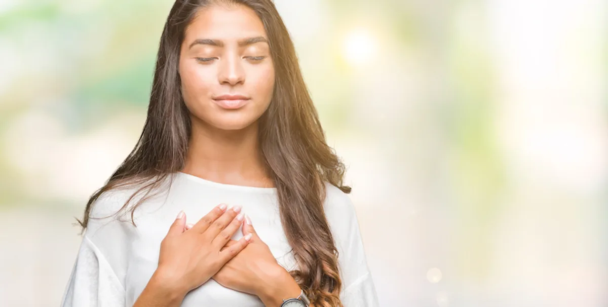 A woman in a white dress, hands folded, embodying gratitude, mirrors 'Thank you for your consideration' in email sign offs.
