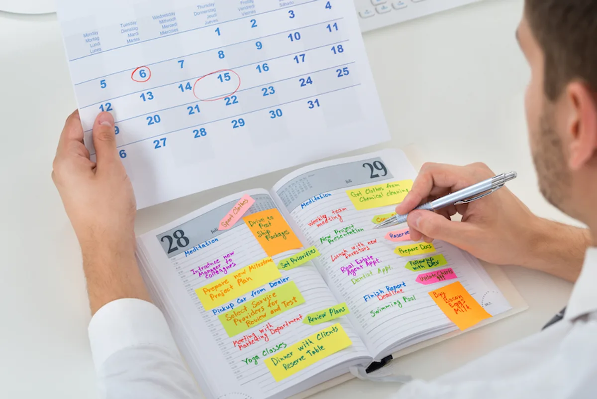 Man with pen in calendar, symbolizing 'Looking forward to [event]' as a thoughtful, contextual email sign off.