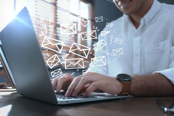 A person typing on a laptop with floating email logos.