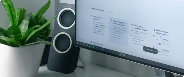 A computer monitor displaying different ideas for a SaaS with a speaker and plants next to it.