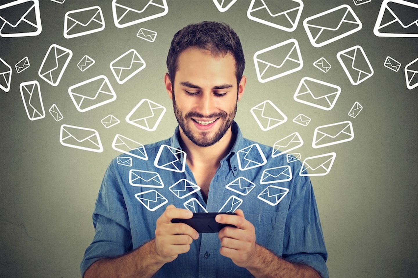 A person typing on their phone surrounding by floating email logos.