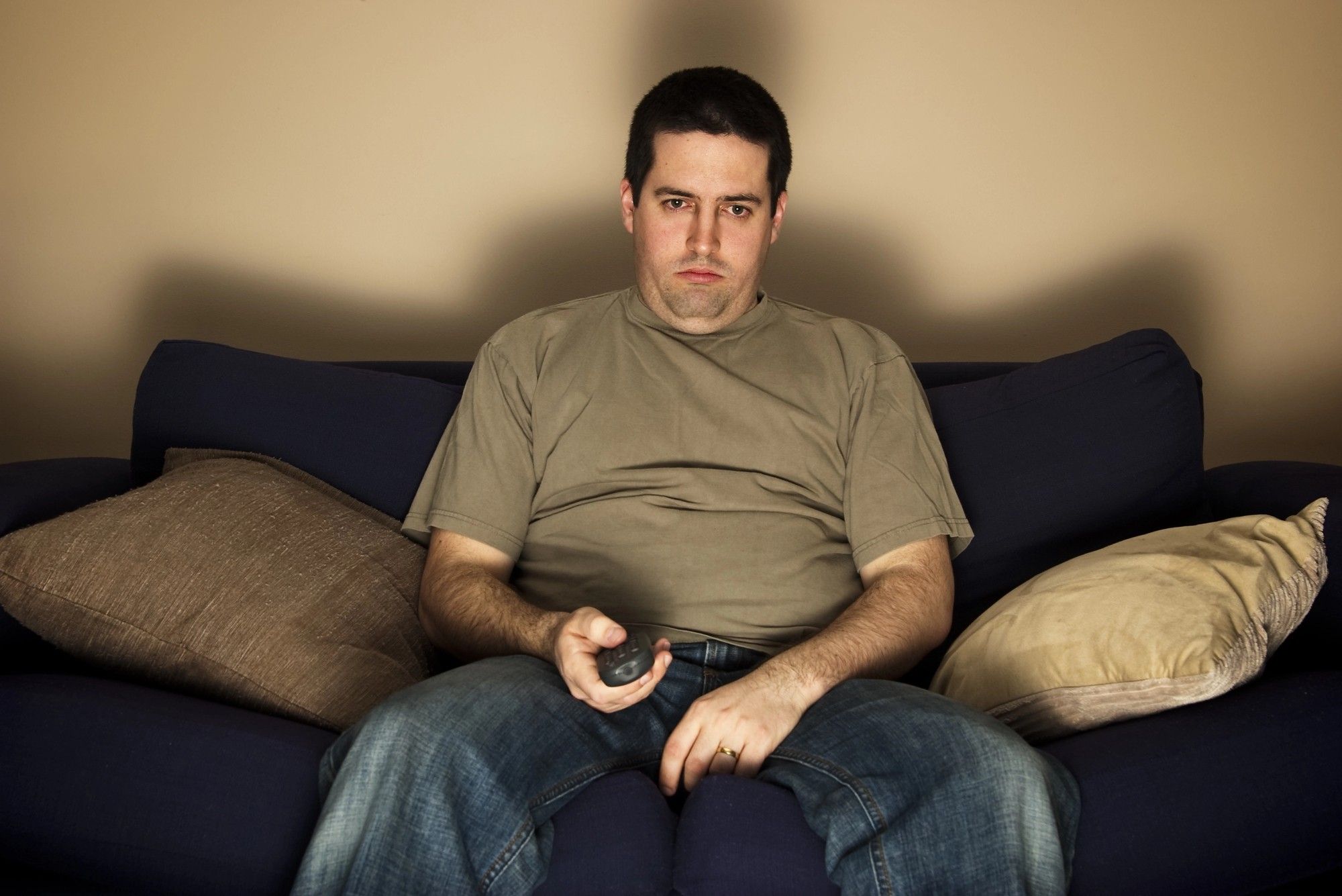 A slouched man on a couch with a remote symbolizes an inactive subscriber showing that pruning readers boosts deliverability.