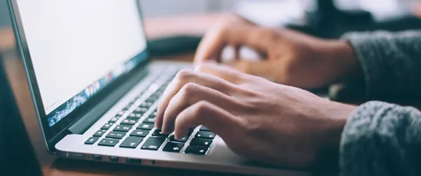 A laptop with a person typing an email.