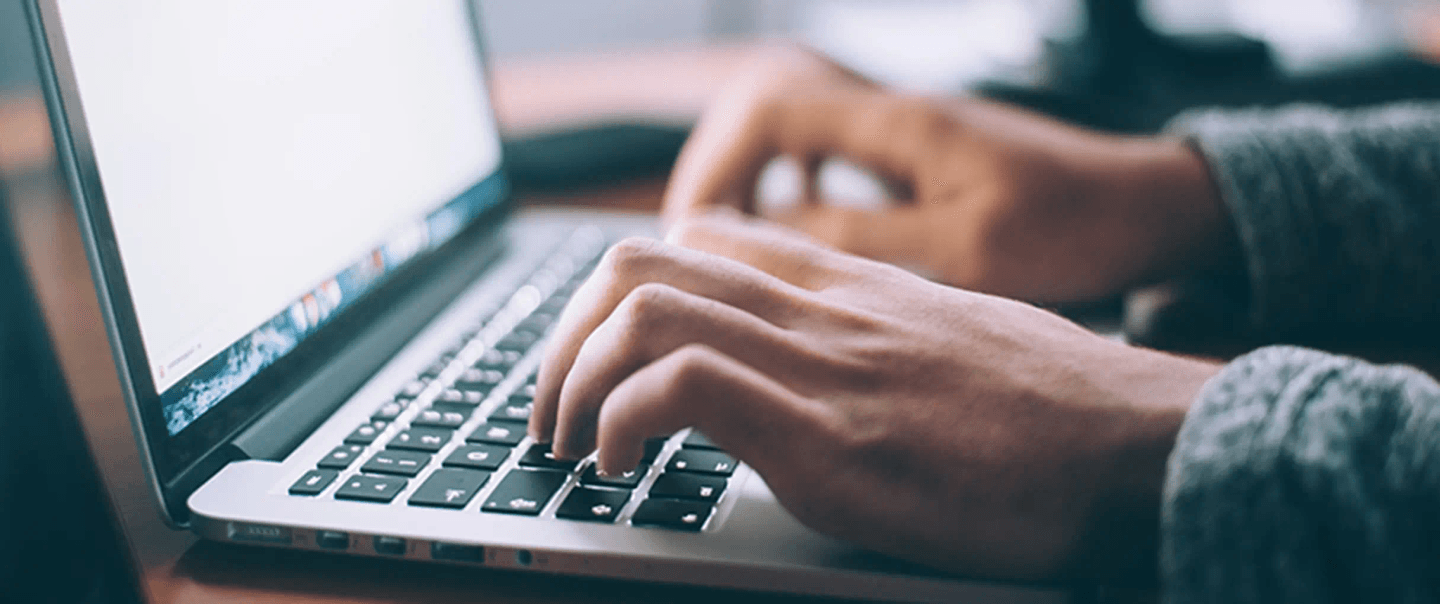 A laptop with a person typing an email.