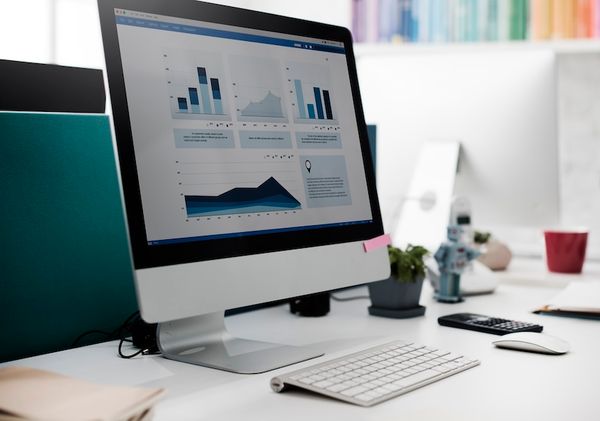 An office desk with a computer monitor displaying email marketing KPIs.