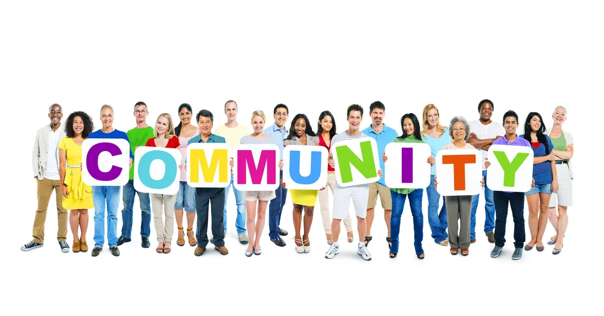 Diverse group of people holding colorful signs spelling 'COMMUNITY', representing connection and shared interests.
